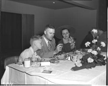 Family at luncheon after meter installation? Father is holding a Gold Medalion home coin