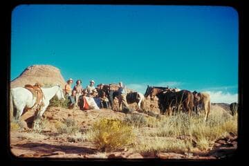 The crew of the Land Cruise of 1955 in Little Finger Canyon, a side canyon of Navajo Canyon. Front: Ballard Atherton, Bahe, Masland, Whitehat. Standing: Marston, Cutler, Visbak, Daly, a Navajo boy of the Manygoats family, Desloge